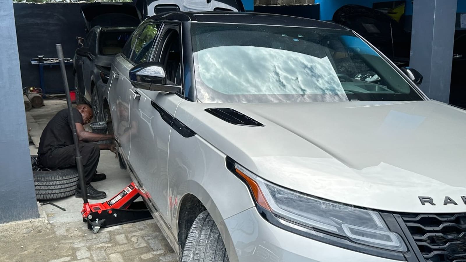 Nigerian technician using electronics diagnostics alongside engine bay work